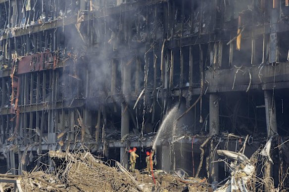 Ukrainian firefighters at the shopping centre site where bombing flattened a car park and gutted an adjacent 10-storey building.