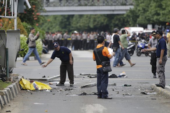 Police officers examine debris at the site where an explosion went off in Jakarta, Indonesia Thursday, Jan. 14, 2016.  Attackers set off explosions at a Starbucks cafe in a bustling shopping area of downtown Jakarta and waged gun-battles with police Thursday, leaving bodies in the streets as office workers watched in terror from high-rise windows.