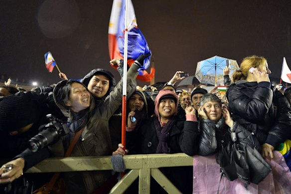 Faithful react as white smoke rises from the chimney on the roof of the Sistine Chapel.