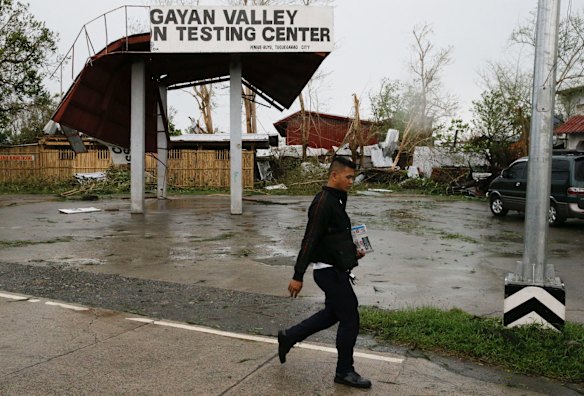 A resident passes by a roof damaged by strong winds from the typhoon.