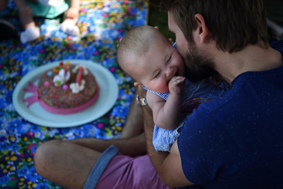 Johnny McElwee holding his giggling daughter at Aviana's 6 month birthday party.