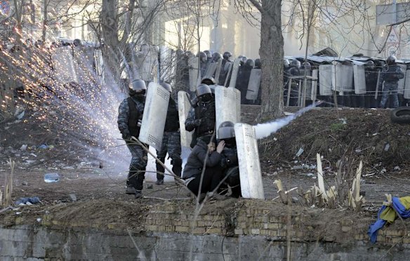 Riot police officers and a woman take cover behind shields during clashes between anti-government protesters with police in Kiev, February 18, 2014. Ukrainian riot police advanced on the heart of 12-week-old protests against President Viktor Yanukovich on Tuesday and security forces set a deadline to end disturbances after at least five protesters were reported killed in a day of clashes.