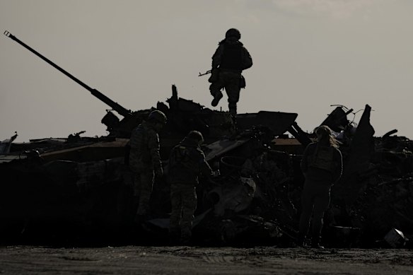 A Ukrainian serviceman walks over a destroyed Russian fighting vehicle in Bucha. Russian troops left behind crushed buildings, streets littered with destroyed cars and residents in dire need of food and other aid in a northern Ukrainian city, giving fuel to Kyiv's calls Thursday for more Western support to help halt Moscow's offensive before it refocuses on the country's east.
