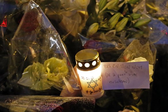 A candle with a pear reading "Not in My Name, From a muslim" is places on a memorial as Members of the Union of French Jewish students attend a demonstration outside a kosher grocery store where four hostages were killed on Friday in Paris, Saturday, Jan. 10, 2015. Hundreds of thousands of people marched Saturday in cities from Toulouse in the south to Rennes in the west to honor the victims, and Paris expects hundreds of thousands more at Sunday?s unity rally. More than 2,000 police are being deployed, in addition to thousands already guarding synagogues, mosques, schools and other sites around France.