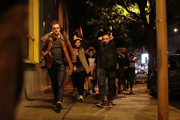 People with their hands on their heads as they leave inside a police cordon after an incident in London.