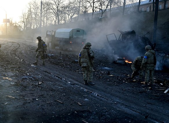 Ukrainian fighters collect unexploded shells early on Saturday after a Russian raid on Kyiv.