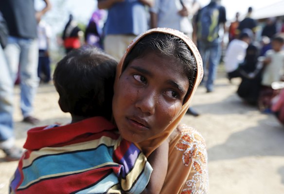 A Rohingya migrant who arrived by boat, holds his child at the port of Julok village in Kuta Binje, Indonesia's Aceh Province, May 20, 2015. Hundreds of Rohingya and Bangladeshi migrants landed in Indonesia's northwestern Aceh province early on Wednesday, an Indonesian search and rescue official said. 

      
