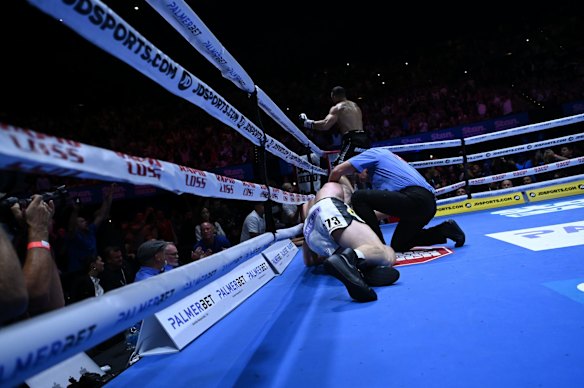 Williams jumps on the ropes to take in the crowd's appreciation as the referee checks on Hall.