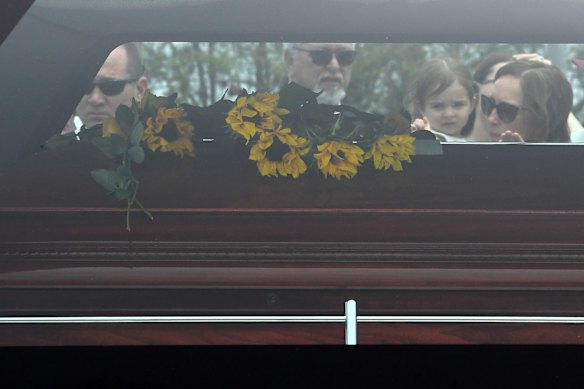 Melissa (right) and Charlotte (2nd from right) O'Dwyer, the wife and young daughter of Rural Fire Service volunteer Andrew O'Dwyer, look on as his casket leaves following the funeral.