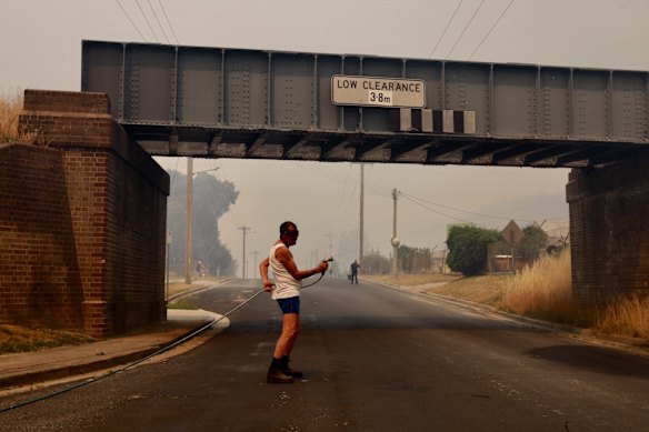 Fire in Lithgow. A local man douses spot fires by the road. 21st December 2019. Photo by Dean Sewell.