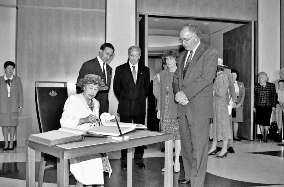 The Queen signs the visitors’ book at Parliament House, while Prime Minister Paul Keating and Parliament House officials look on, February 1992.