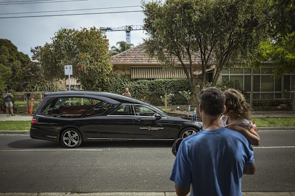 20/03/22 Shane Warne's body is farewelled by local fans Julian Toohey and daughter Isadora,3, as he leaves St Kilda Football Club, Moorabbin after a private memorial service. Photograph by Chis Hopkins