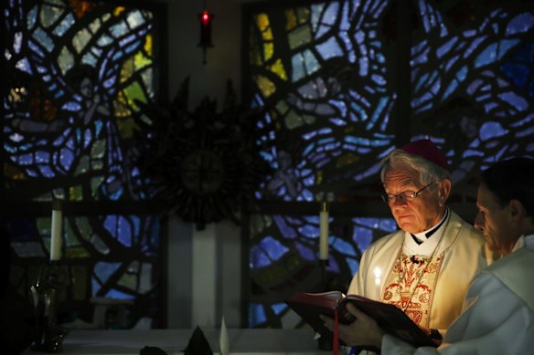 Bishop George Leo Thomas, left, gives an Easter Vigil Mass beside Deacon Rick Minch live-streamed from a small chapel without worshipers due to the coronavirus outbreak, in Las Vegas.