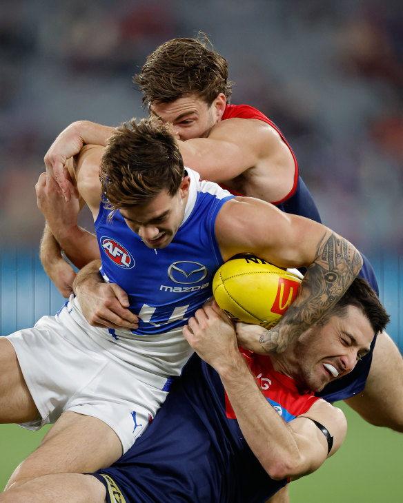 Jy Simpkin of the Kangaroos is tackled by Jack Viney of the Demons (top) and Alex Neal-Bullen of the Demons (bottom).