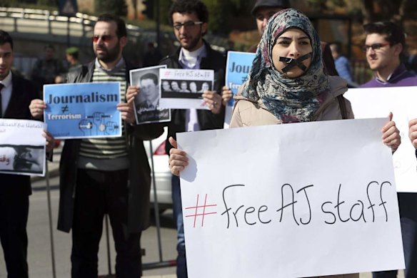 A protester, with a taped mouth, stands with a sign during a protest against the detainment of Al Jazeera journalists in Egypt, in Beirut February 8, 2014.