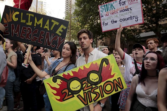 Australian actor Lincoln Younes and Natasha Liu Bordizzo hold hand made signs as thousands gather at Town Hall.