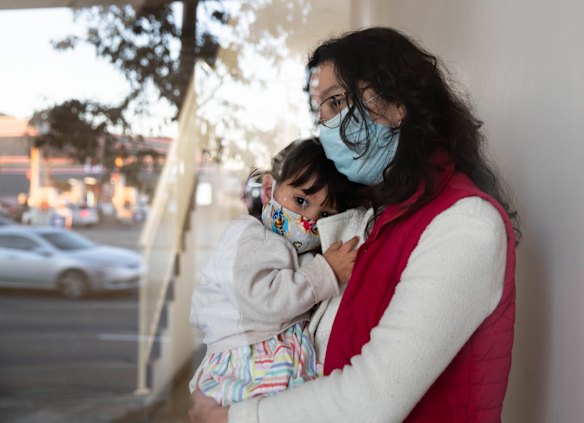 Leidy Castro Meneses with her daughter, Sofia, in the lobby of their Yagoona apartment building. She is relieved to be vaccinated now that the virus is raging in her local area and also because her husband went back to their native Colombia for two months after his father died from COVID-19.