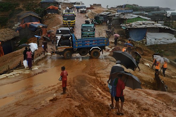 Trucks, rickshaws and people negotiate their way through the mud after a monsoon downpour in Kutupalong Camp.