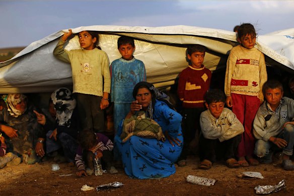 Syrian Kurdish refugees shield themselves from rain after crossing into Turkey from the Syrian border town Kobani, near the southeastern Turkish town of Suruc in Sanliurfa province October 2, 2014.  Photo by Reuters
