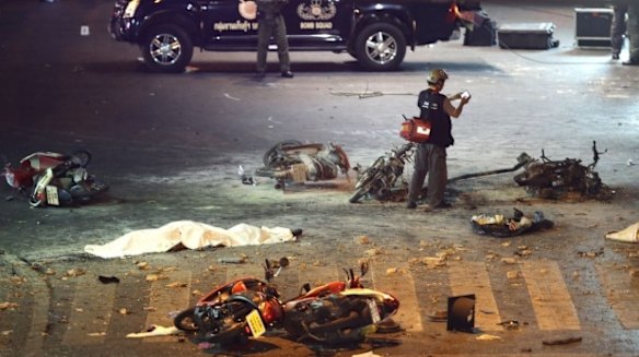 A policeman photographs debris from an explosion in central Bangkok, Thailand.