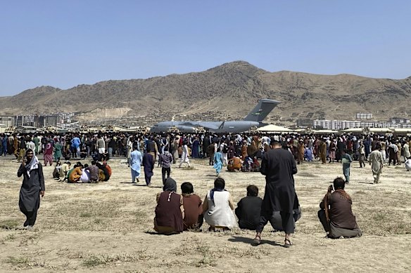 Hundreds of people gather near a U.S. Air Force C-17 transport plane at a perimeter at the international airport in Kabul, Afghanistan. On Monday, the U.S. military and officials focus was on Kabul's airport, where thousands of Afghans trapped by the sudden Taliban takeover rushed the tarmac and clung to U.S. military planes deployed to fly out staffers of the U.S. Embassy.
