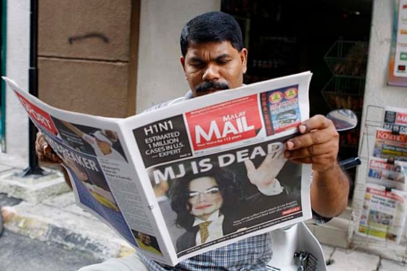 A man reads a afternoon paper in Kuala Lumpur, Malaysia, with the announcement that US rock legend Michael Jackson had died, Friday, June 26, 2009.