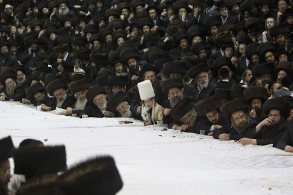 An Ultra-Orthodox Jewish boy stands amongst men during celebrations.