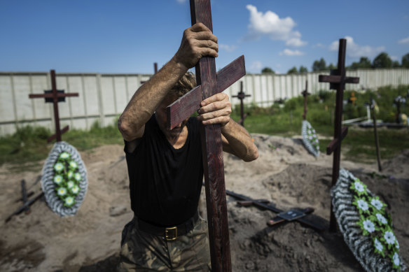 A funeral worker installs a cross with a number plate on the grave of an unidentified civilian killed by Russian troops during the Russian occupation in Bucha near Kyiv, Ukraine