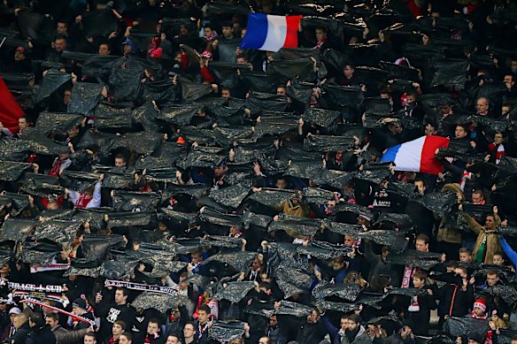 Reims' supporters hold black flags in tribute to the victims of  three days of terror and twin siege dramas that claimed 17 victims, including the victims of the first attack by armed gunmen on the offices of French satirical newspaper Charlie Hebdo in Paris on January 7, prior to the French L1 football match between Reims (RS) and Saint-Etienne (ASSE) on January 10, 2015 at the Auguste Delaune stadium in Reims, eastern France.