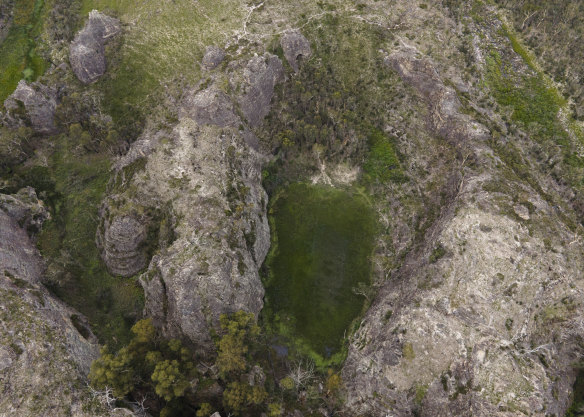 An aerial view of Gooch’s Crater near the Gardens of Stone National Park, with larges patches of pink flannel flowers on display.