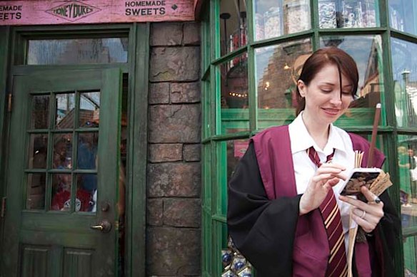A guest, in her Hogwarts school regalia, uses a mobile phone during the grand opening for The Wizarding World of Harry Potter.