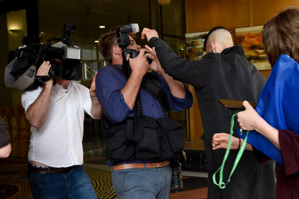 Menouar Belkadi pushes past photographers as he arrives at the Downing Centre Court in Sydney on Friday.