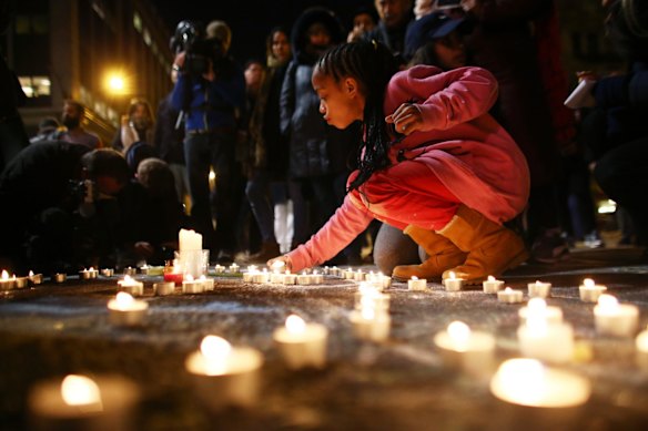 A young girl lights a candle at the Place de la Bourse.