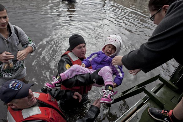 Members of a New York Police Department tactical team rescue Haley Rombi, 3, in the Dongon Hills neighborhood of the Staten Island borough of New York, Oct. 30, 2012. (Michael Kirby Smith/The New York Times)