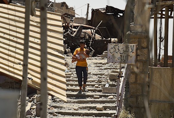 A teenage boy carries a baby as he flees Islamic State.