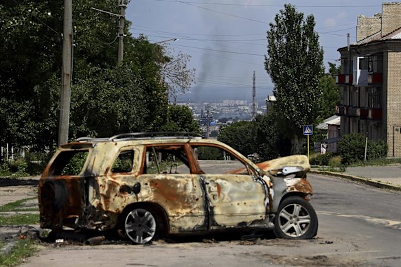 The remains of a vehicle on a road in Lysychansk where smoke can be seen rising from the besieged city of Sievierodonetsk. Lysychansk in eastern Ukraine was once home to 100,000 people but now is a hollowed-out city at the centre of the war. Lysychansk, Ukraine.