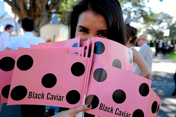 Grace Tai weilds Black Caviar flags at Royal Randwick.