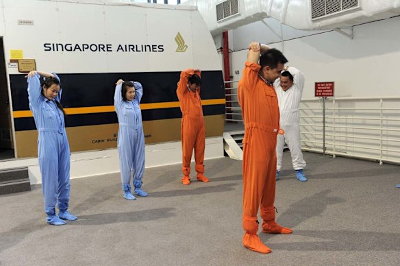 Singapore Airlines cabin crew warm up before performing a land evacuation exercise from a mock-up plane.