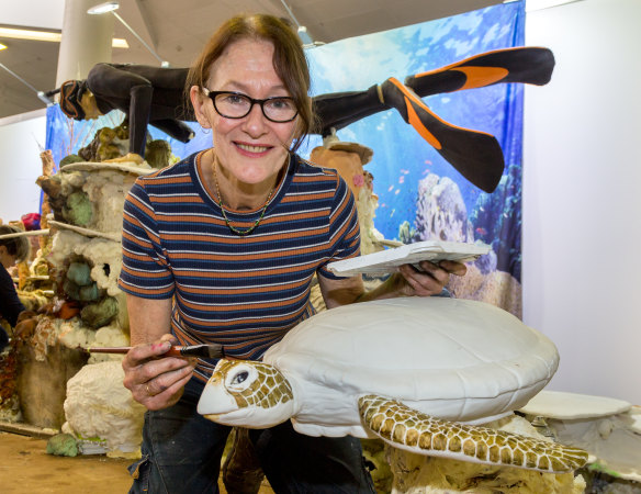 Cake artist Margie Carter helping paint the cake that includes a shark, diver and a turtle.