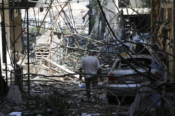 A man walks through debris on a residential street, devastated by an explosion a day earlier.