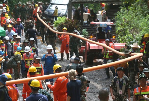 Rescuer carry water pipe makes their way up at the entrance to a cave