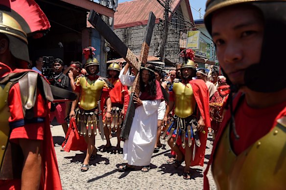 Reuben Enaje (centre) playing the role of Jesus, carries the cross through the streets of Barangay San Pedro Cutud.