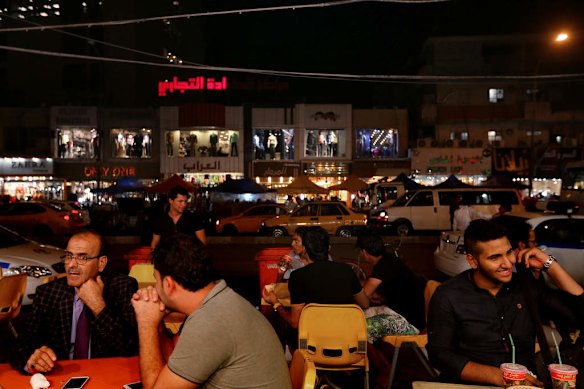 Iraqi men sit at a restaurant with friends on Karada street in the Karada area of Baghdad.