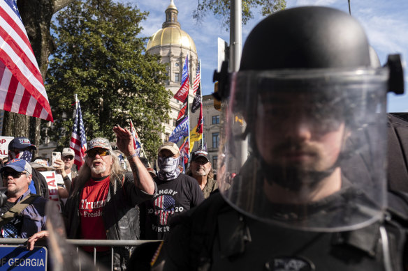 2020 年 11 月 21 日，亚特兰大乔治亚州议会大厦外，一名身穿防暴装备的军官站在唐纳德·特朗普的支持者和反抗议者之间。