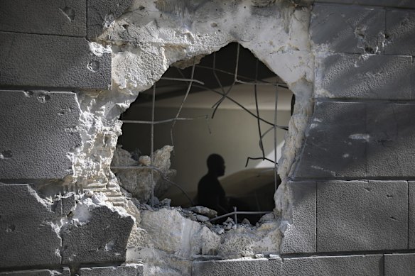 A man is seen through a hole in a wall of a residential building after it was struck by a rocket fired from the Gaza Strip in Ashkelon, Israel, Friday, May 14, 2021. Israeli artillery pounded northern Gaza early Friday in an attempt to destroy a vast network of militant tunnels inside the territory, the military said, bringing the front lines closer to dense civilian areas and paving the way for a potential ground invasion.