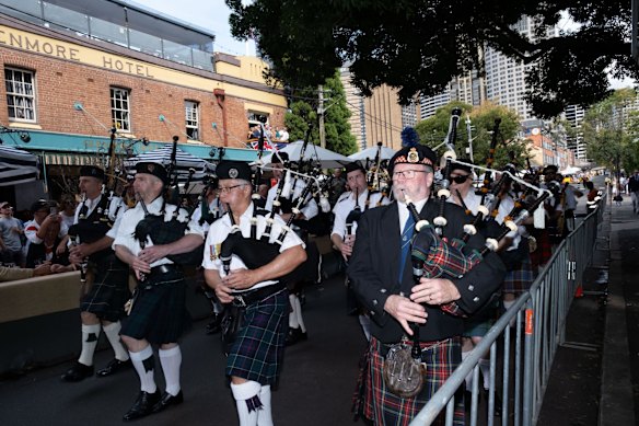 A pipe band passes by people celebrating ANZAC Day at the Glenmore hotel in The Rocks, Sydney.