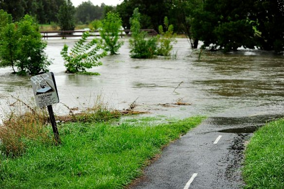 Floodwater in Ginninderra Creek flows under Ginninderra Drive near Charnwood, Queanbeyan.