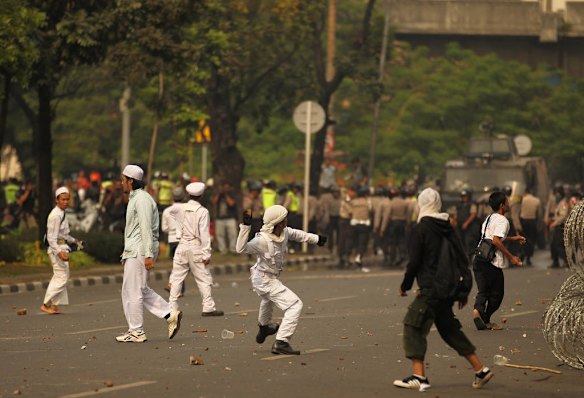 Protestors throw rocks as Indonesian police release tear gas at anti American protests infront of the US Embassy in Jakarta, Indonesia.