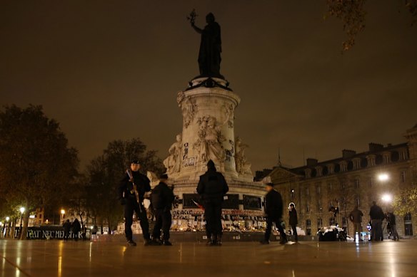 Police at the Place de la Republique where a memorial honouring 129 people killed by terrorists grows in Paris, France