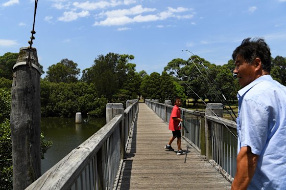 Andrew Li, 10, walks over a footbridge with his grandfather after fishing on the Cooks River at Boat Harbour in Hurlstone Park, Sydney.